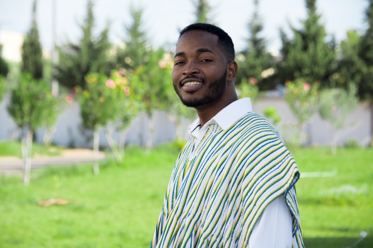 Dr. Tawfiq Abu standing outside surrounded by trees, grass and nature dressed in a traditional Ghanian outfit.